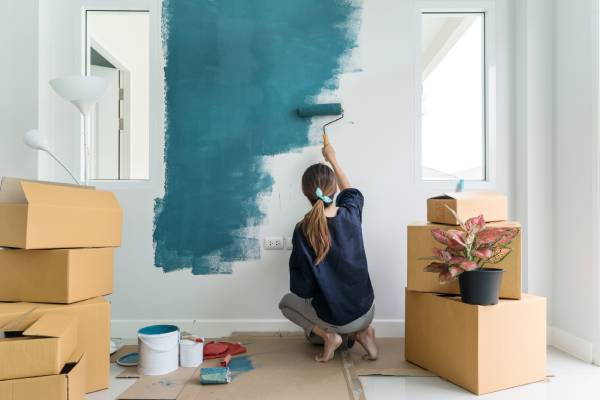 Jeune femme en train de repeindre son mur avec une peinture pour intérieur